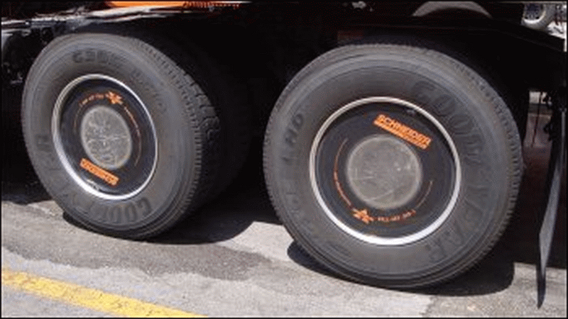 A close-up of a wheel cover on a drive tire of a Schneider tractor.