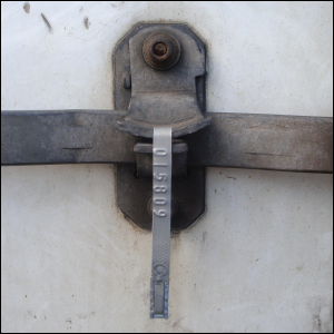 Metal seal inserted through locking device over trailer bar handles. Does not act as a trailer door lock.