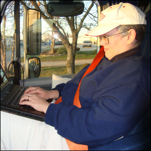 Vicki Simons, seated in the passenger seat of a semi tractor trailer, is wearing a seat belt.